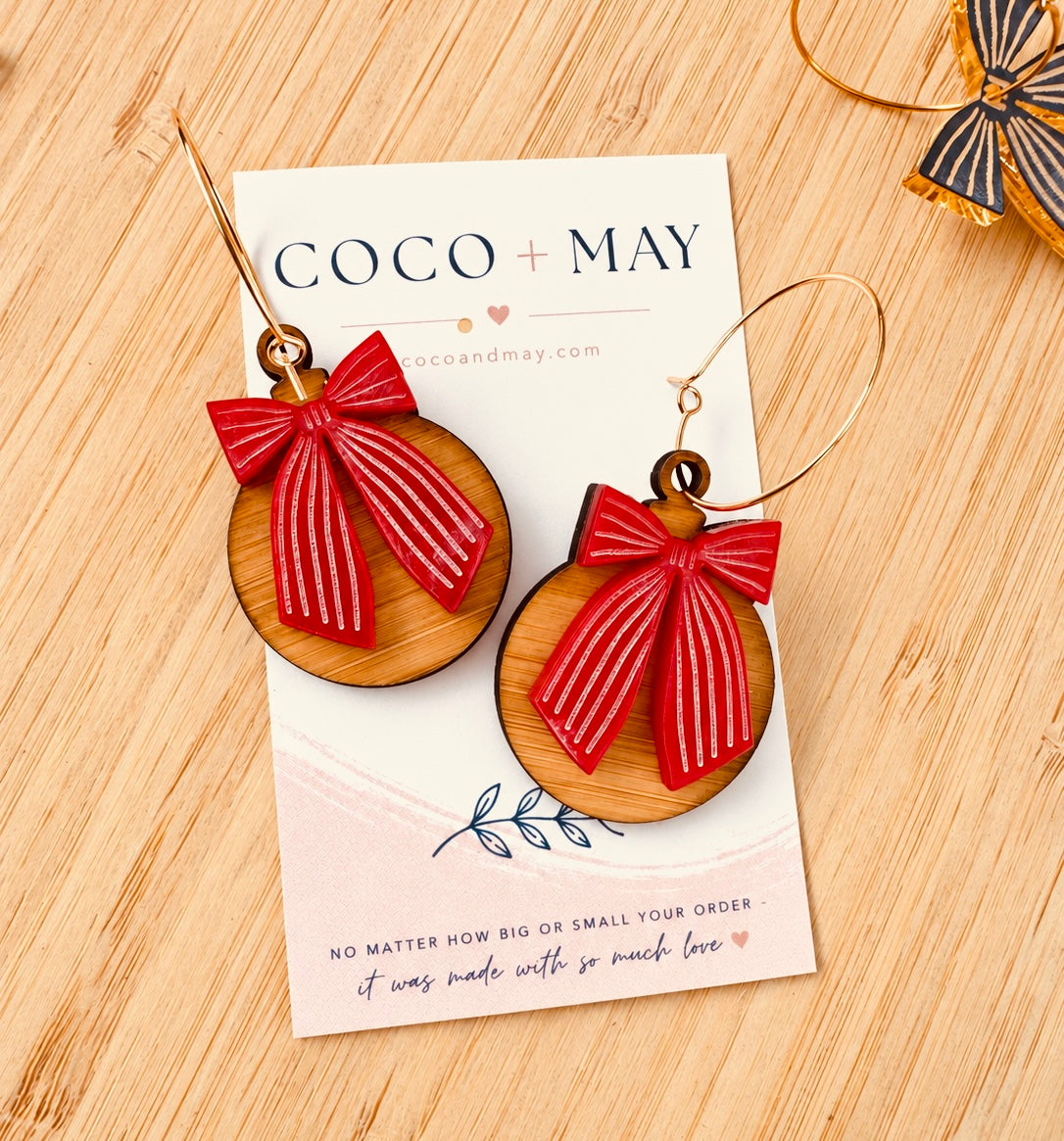 Red and pink striped bow earrings hanging from gold-tone hoops, displayed on a Coco & May jewellery card
