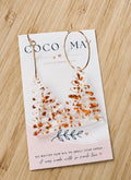 Clear acrylic Christmas tree dangle earrings with chunky gold acrylic details, displayed on a Coco & May jewellery card