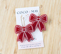 Red and white statement bow dangle earrings with contrasting decorative outlines, displayed on a Coco & May jewellery card