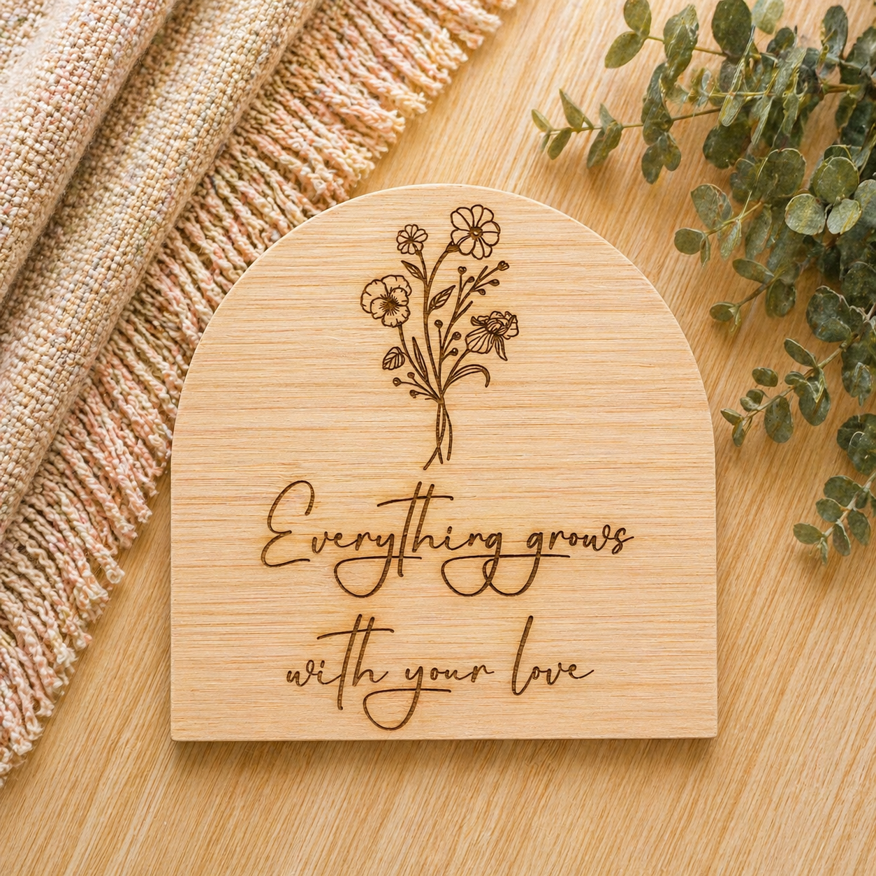Engraved wooden plaque with floral design and quote “everything grows with love”, styled as nursery or Mother’s Day gift
