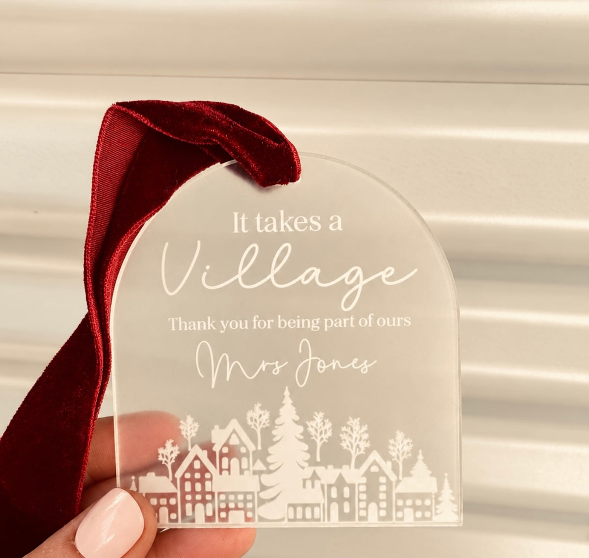It Takes a Village Christmas ornament with white Christmas village illustration, elegant arch shape and burgundy velvet ribbon by Coco & May