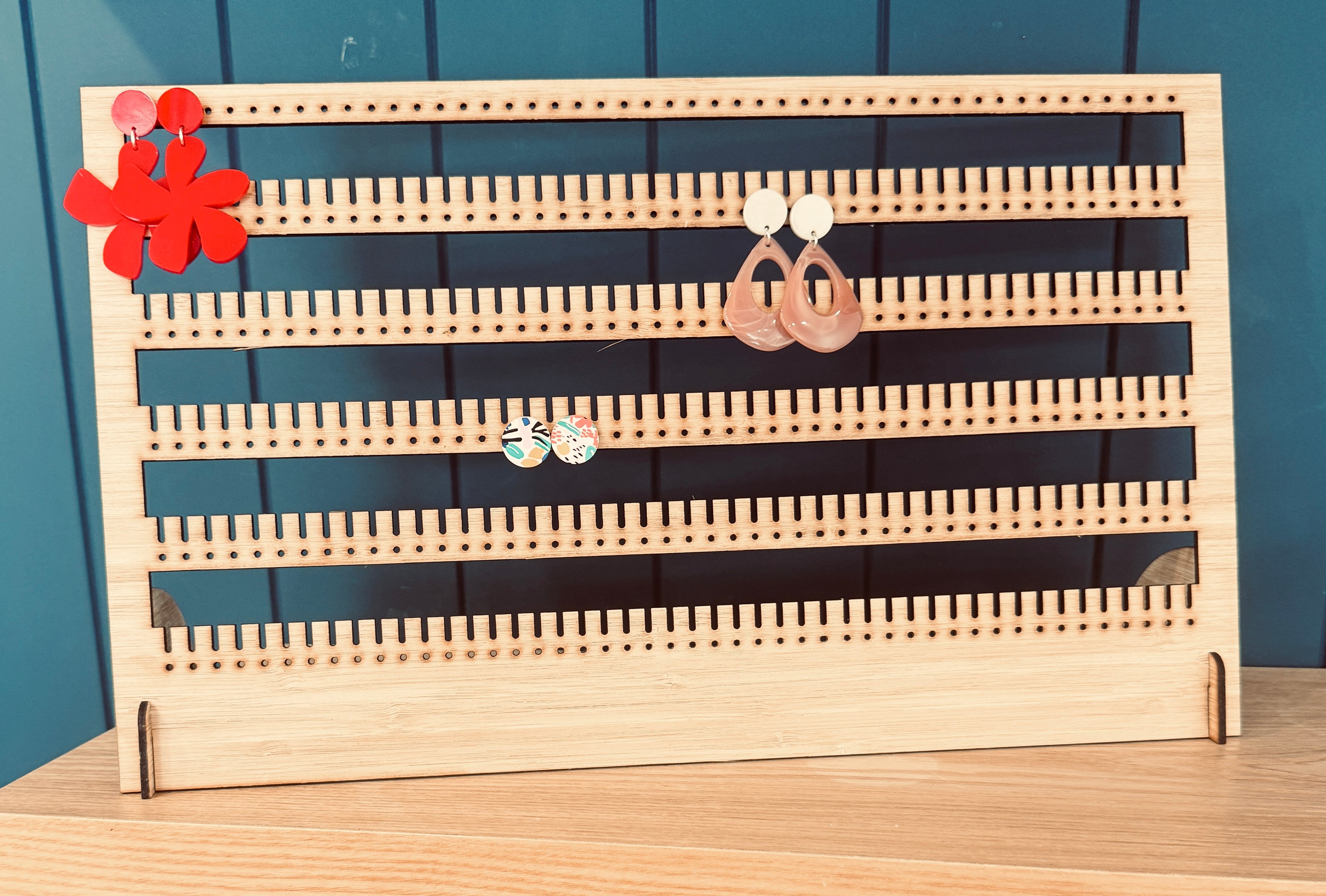 Bamboo earring stand holding over 100 pairs of earrings, displayed on vanity table."