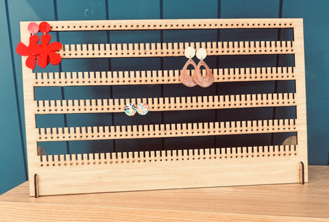 Bamboo earring stand holding over 100 pairs of earrings, displayed on vanity table."