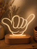 Shaka hand LED night light glowing warm on wooden base, styled for kids or teen bedroom decor
