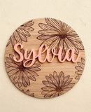Round wooden plaque with engraved daisies and raised acrylic name